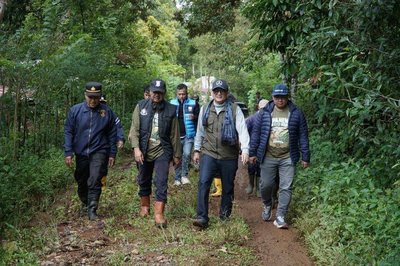 alt="Ariansyah Kadis Kominfo Jambi berjalan di jalur ekstrem diguyur hujan menuju lokasi panen kopi Kerinci"