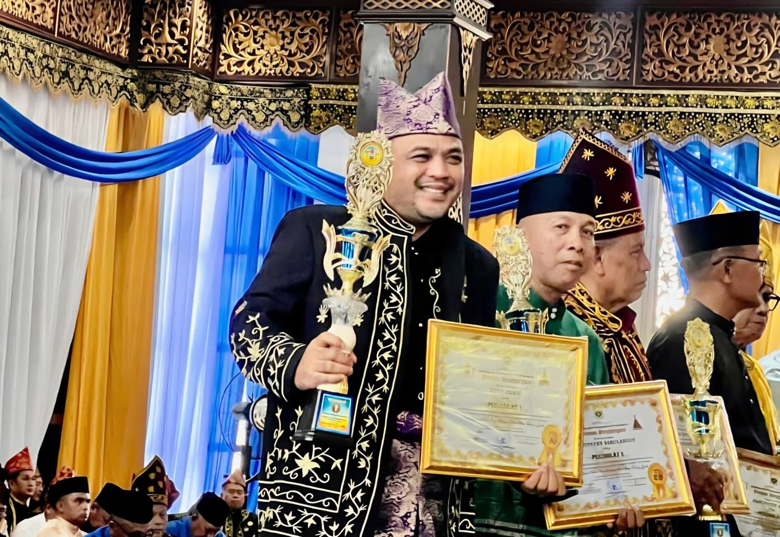 alt="Ketua LAM Kota Jambi Datuk Aswan Hidayat saat menerima piala juara satu lomba apresiasi dari Gubernur Jambi Al Haris"