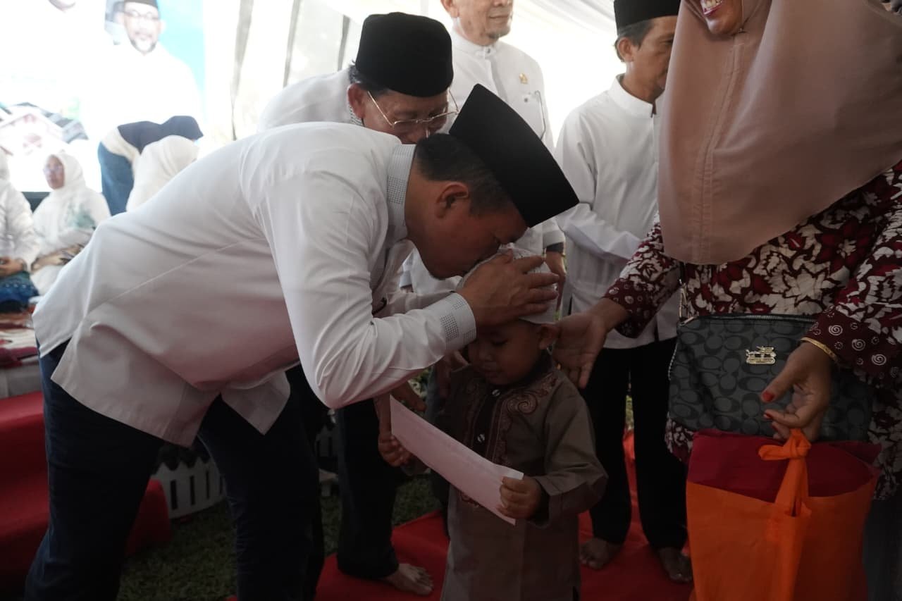 alt="Gubernur Jambi Al Haris saat mengusap kepala dan menyerahkan bantuan uang tunai kepada anak yatim di Lapangan Kantor Gubernur"
