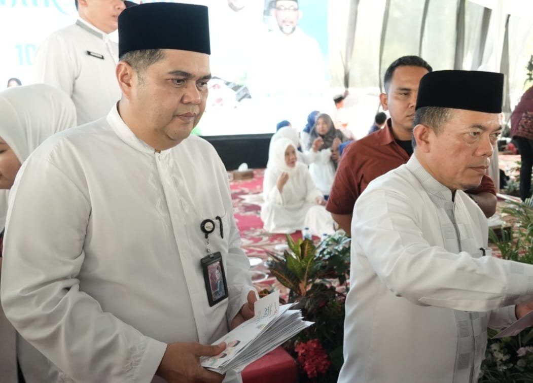 alt="Direktur Operasional Bank Jambi Zulfikar saat menyerahkan amplop santunan kepada anak yatim di Lapangan Kantor Gubernur"
