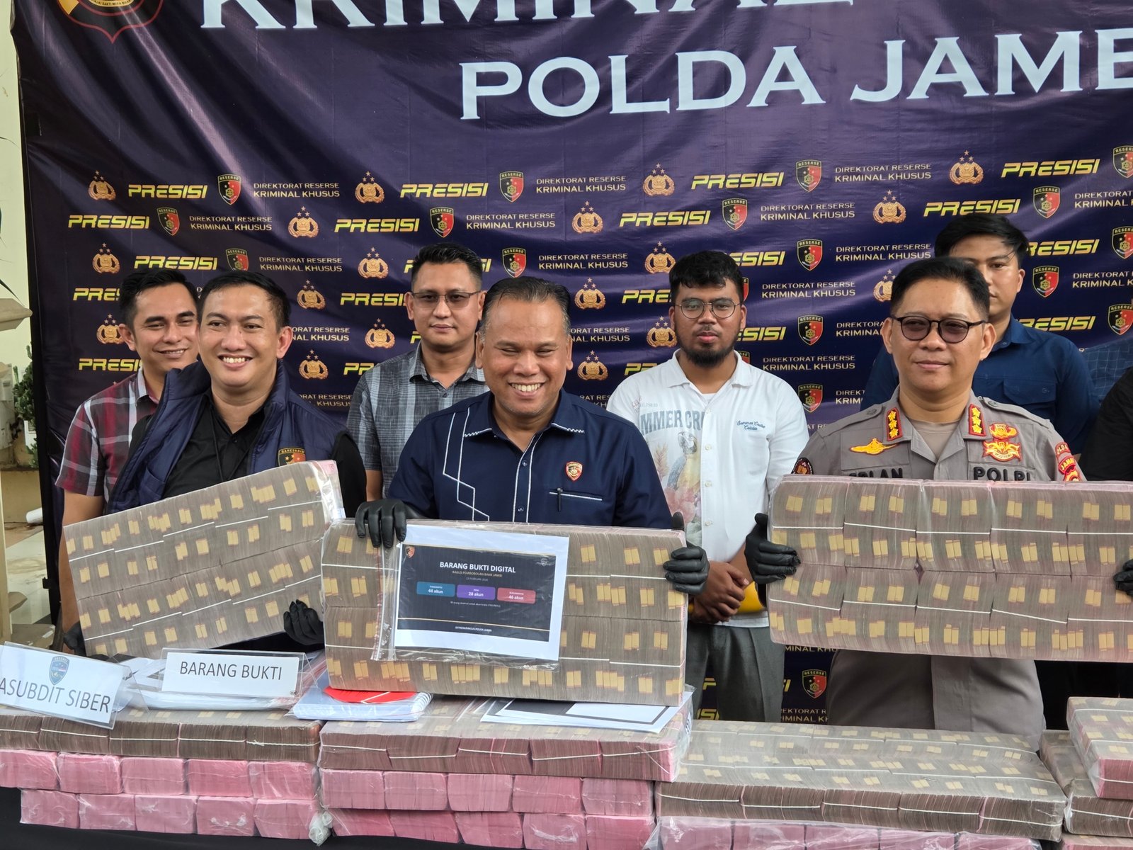 alt="Dirreskrimsus Polda Jambi Kombes Pol Taufik Nurmandia memegang barang bukti digital forensik di depan awak media"