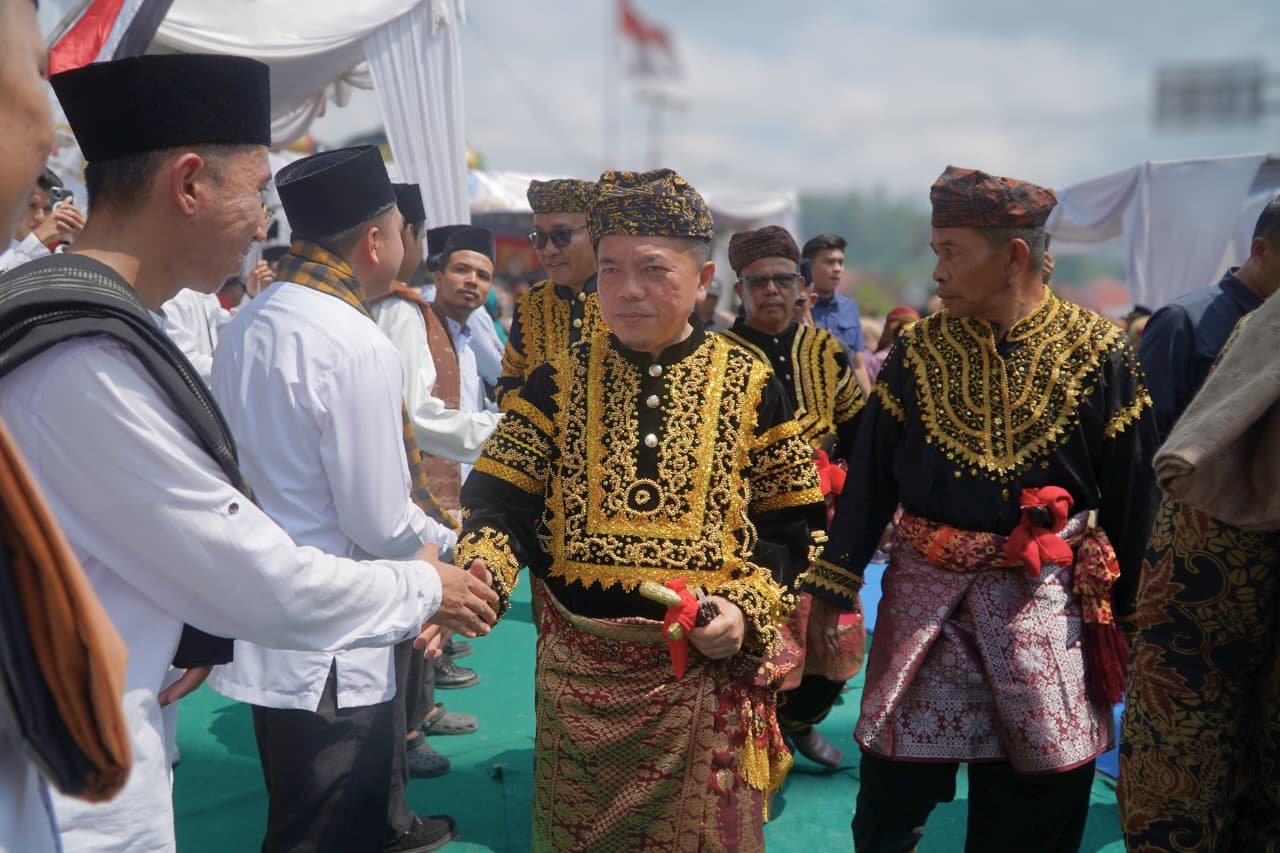 alt="Gubernur Jambi Al Haris didampingi istri mengenakan pakaian adat kebesaran saat dianugerahi gelar Depati Amanah Negroi"