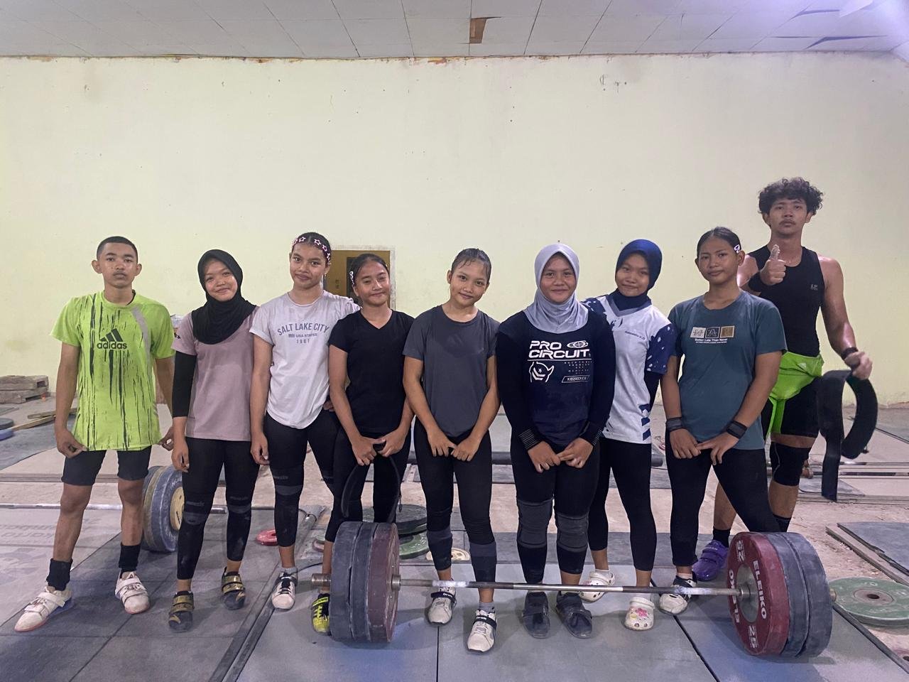 alt="Sembilan lifter muda Jambi kategori youth dan junior berfoto bersama tim pelatih saat latihan angkat besi"
