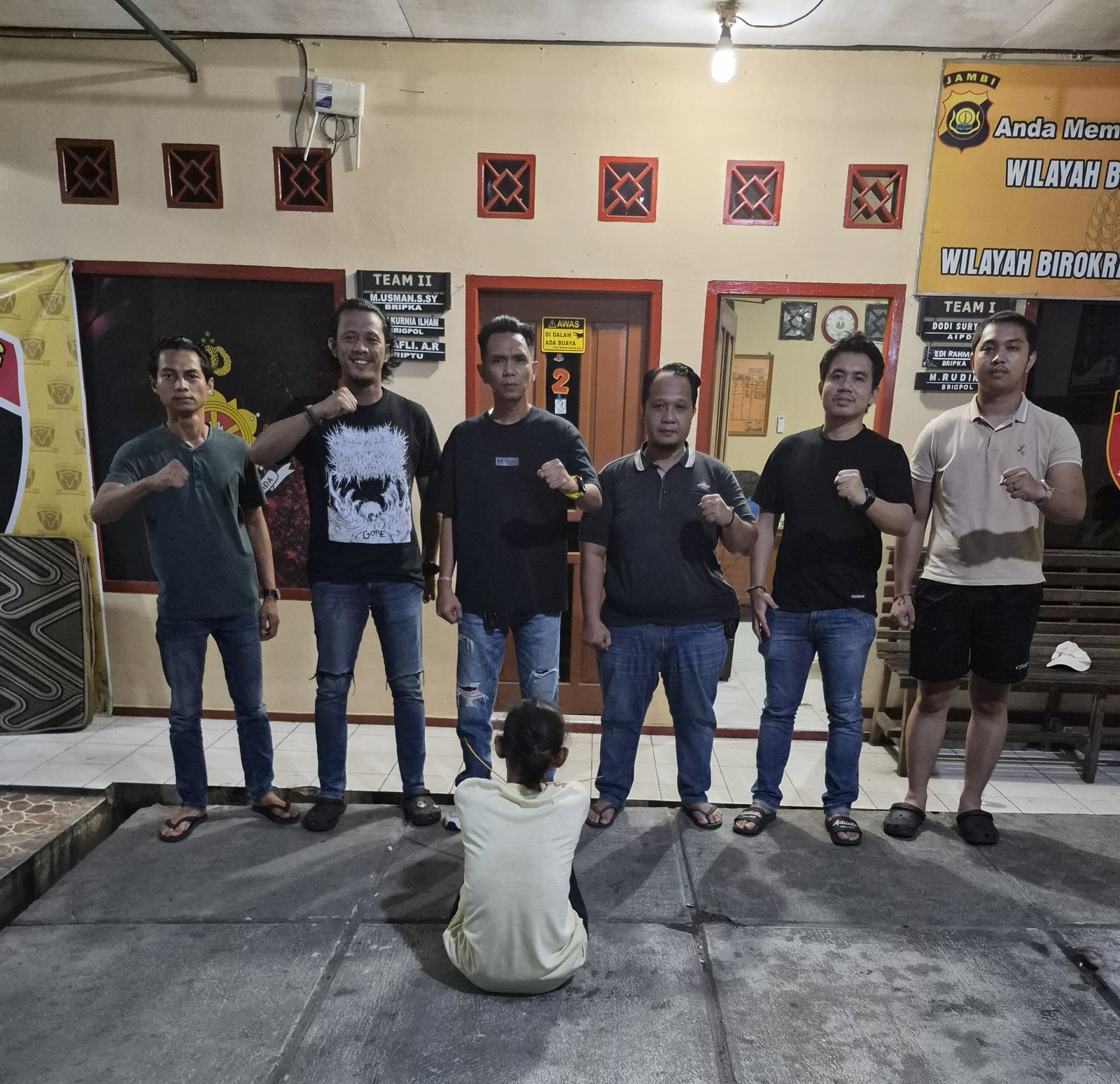 alt="Tersangka Mariyadi mengenakan baju tahanan berdiri di samping barang bukti kasur yang diamankan Ipda Ondo Siburian"