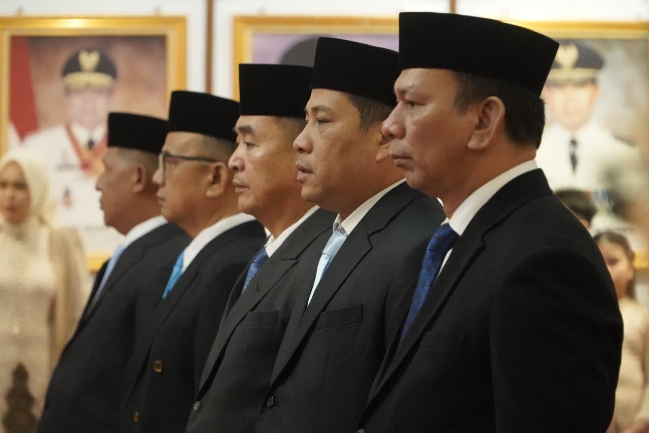 alt="Umar My dan drg Iwan Hendrawan mengenakan pakaian jas lengkap sedang menandatangani dokumen pelantikan"