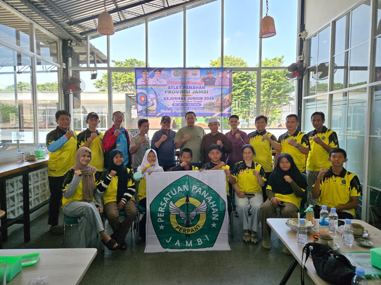 alt="Tujuh pemanah muda Jambi memakai seragam kontingen membentangkan spanduk siap bertanding ke Kudus"