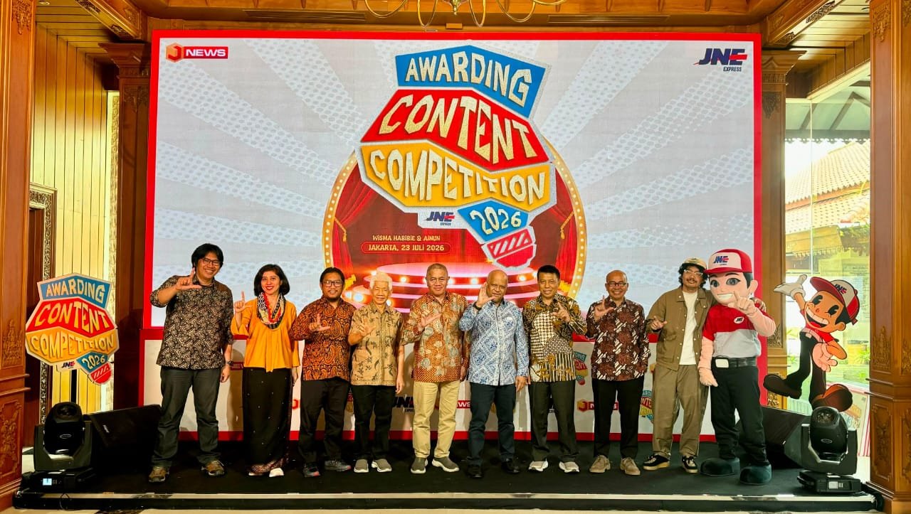 alt="Presiden Direktur JNE M Feriadi Soeprapto bersama Ilham Akbar Habibie menyerahkan trofi di panggung"