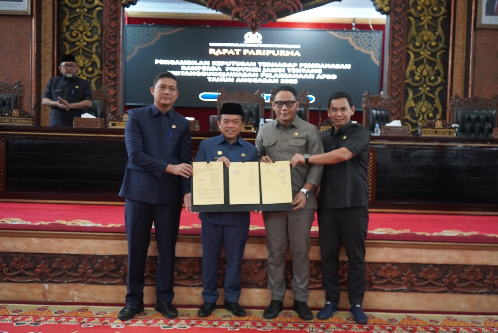 alt="Gubernur Jambi Al Haris menandatangani berkas dokumen Perda APBD 2025 di podium Gedung DPRD"