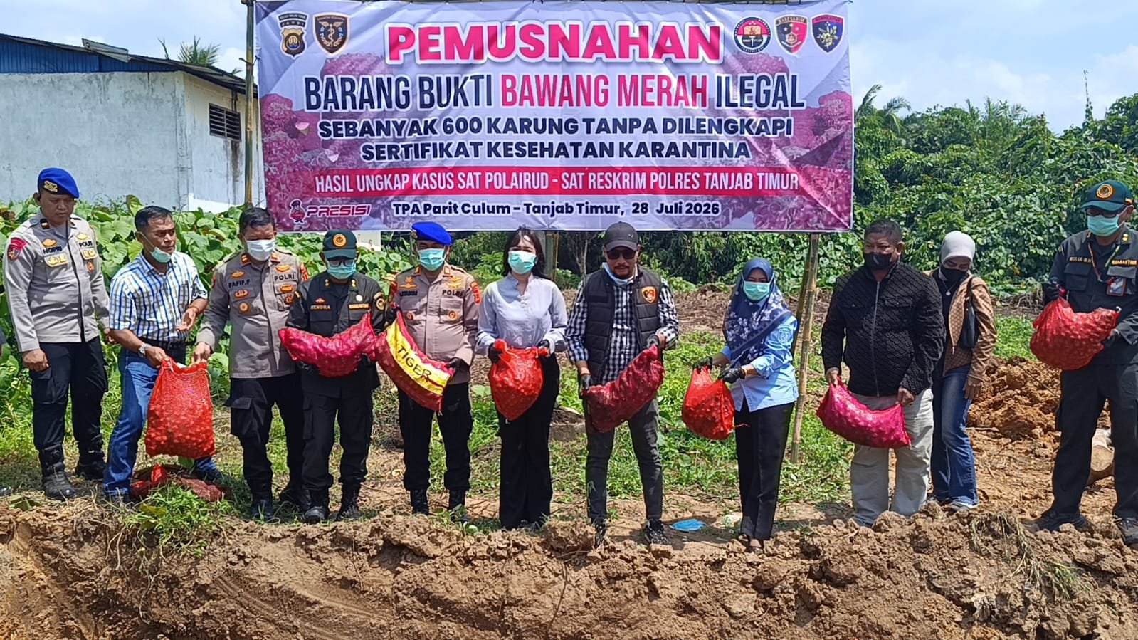 alt="Aparat Polres Tanjab Timur bersama petugas Balai Karantina menyaksikan pemusnahan ratusan karung bawang merah ke dalam lubang tanah"