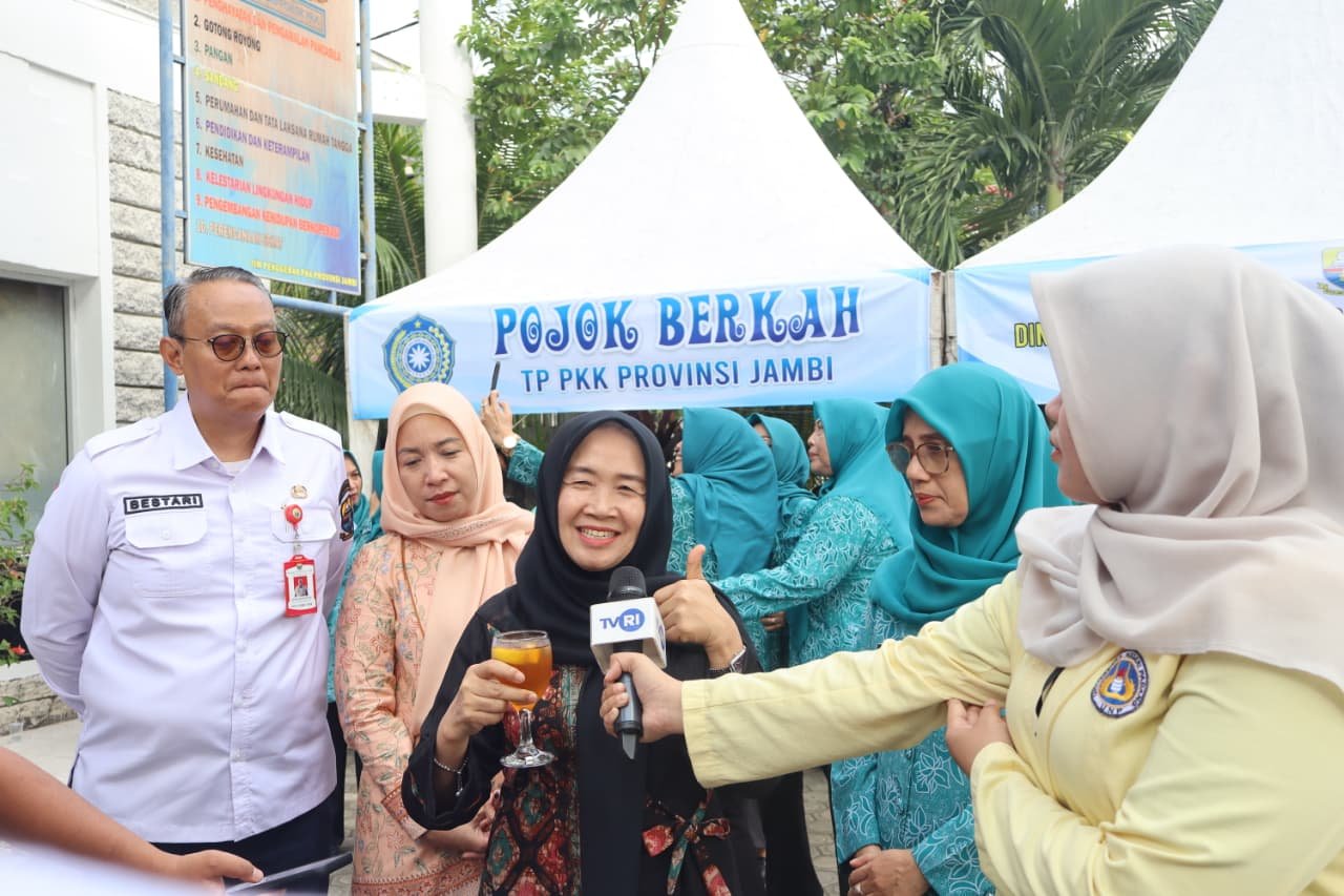 alt="Ketua TP PKK Provinsi Jambi Hesnidar Haris tersenyum saat memberikan hadiah Al-Qur'an kepada seorang ibu di Sekretariat PKK"