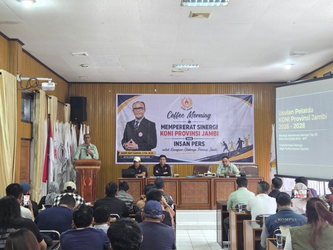 alt="Ketua Umum KONI Jambi Mat Sanusi berbicara di depan puluhan jurnalis olahraga saat acara coffee morning"