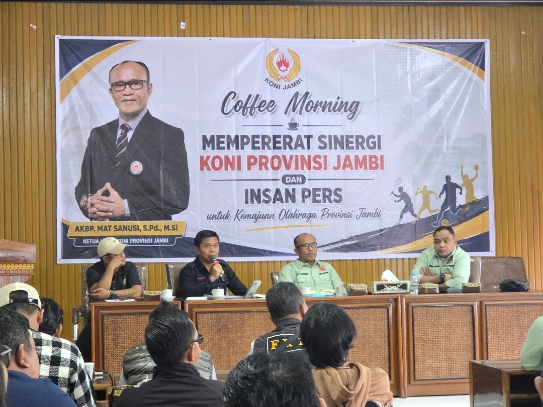alt="Sekum KONI Jambi Muhammad Ali berbicara serius menggunakan mikrofon menjelaskan konsep sport science"