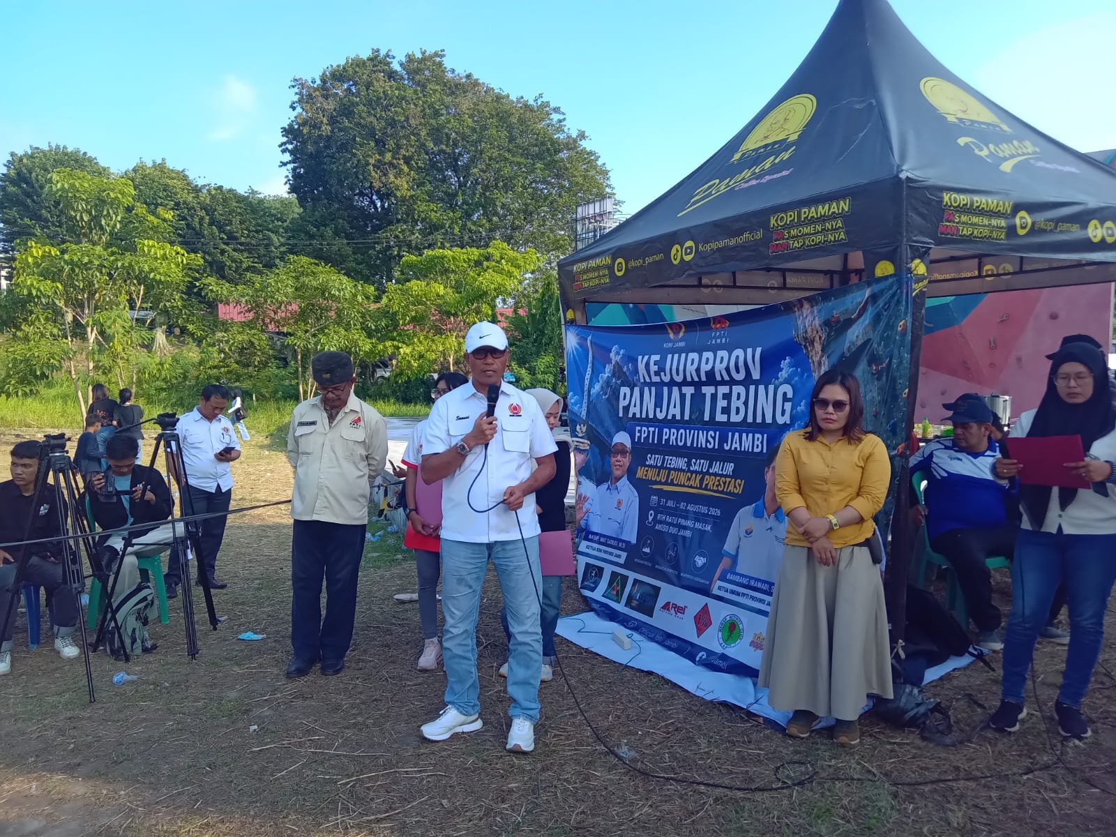 alt="Ketua Umum KONI Jambi Mat Sanusi berdiri memberikan arahan di depan dinding panjat tebing FPTI"