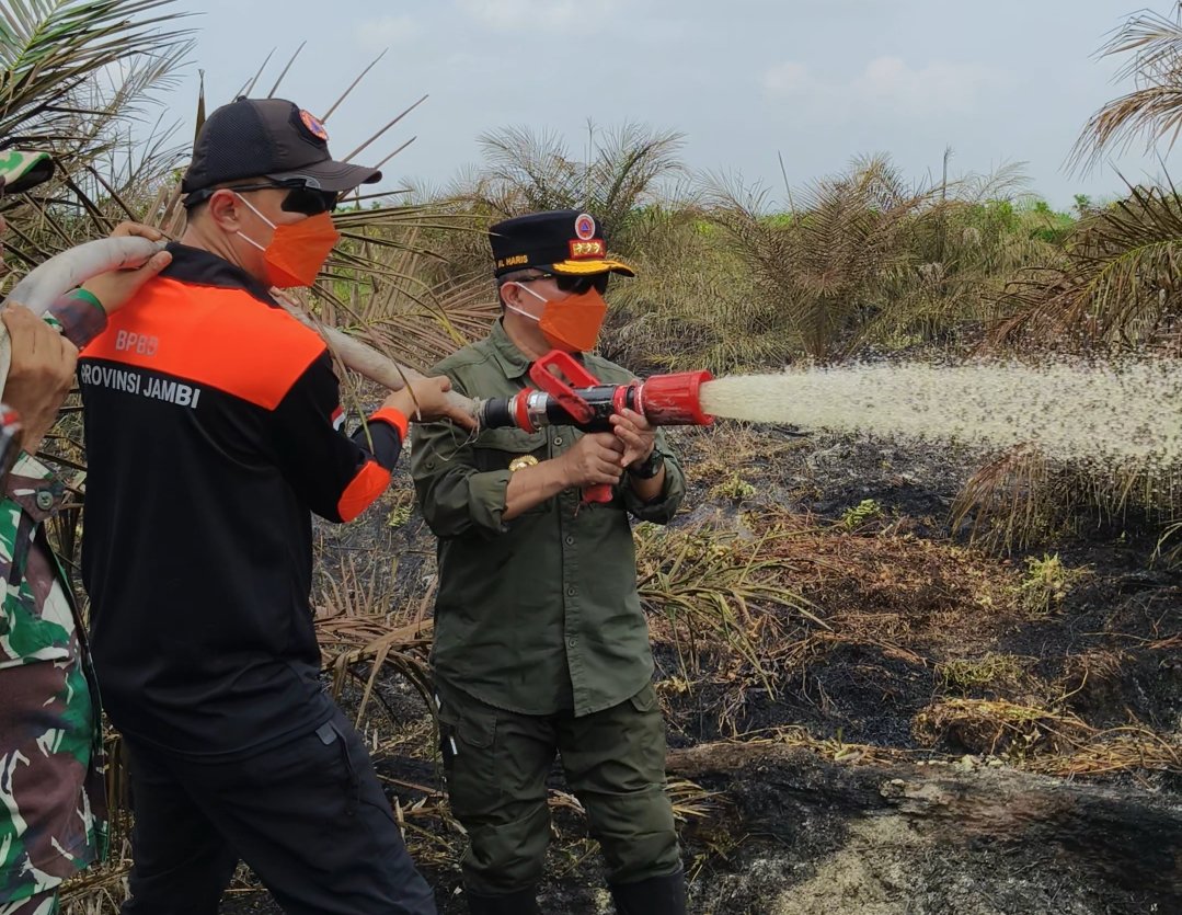 alt="Gubernur Jambi Al Haris memegang selang memadamkan api di lahan gambut Sungai Gelam Muaro Jambi"