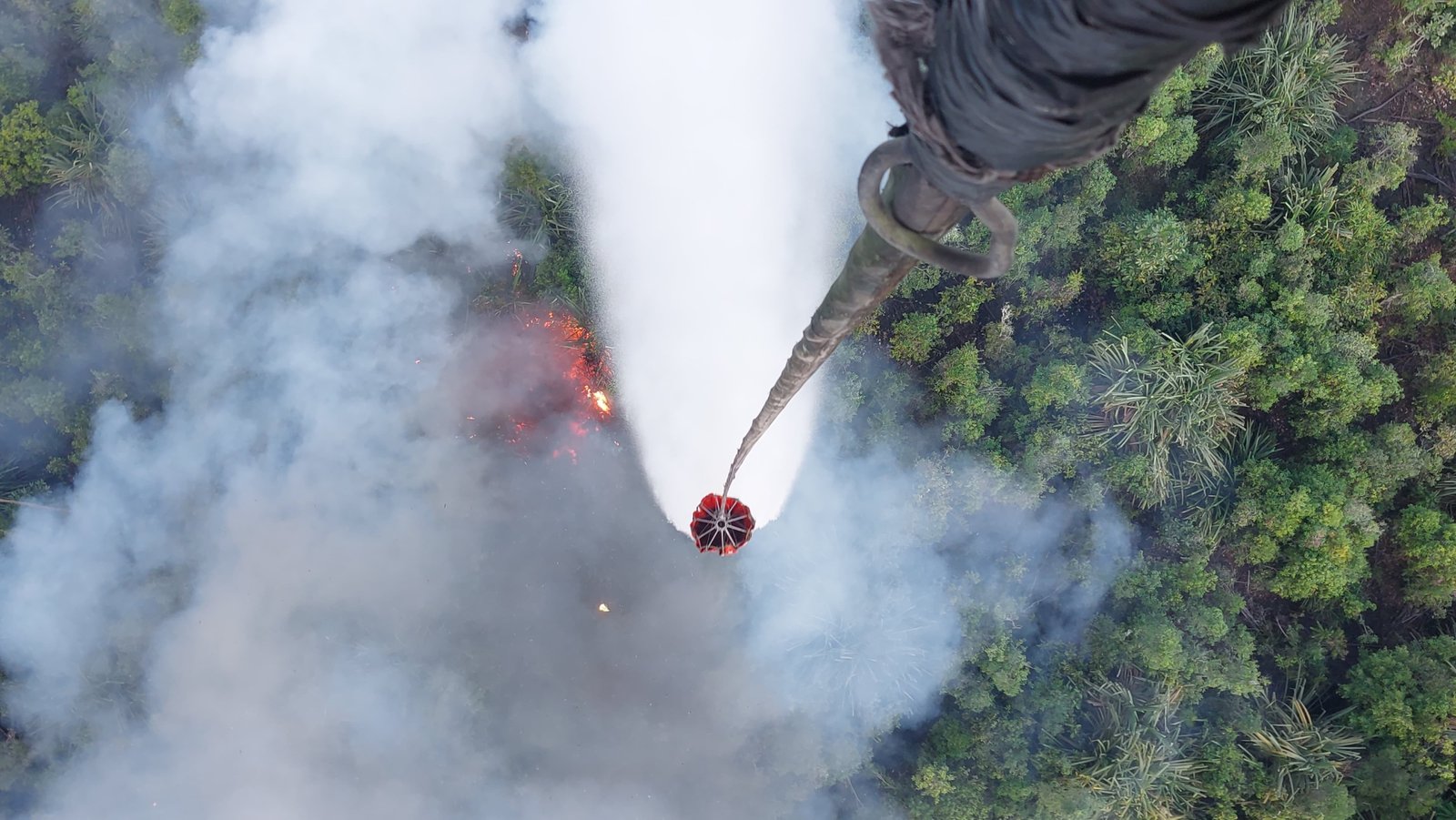 alt="Helikopter water bombing dan personel PT WKS APP Group saat melakukan pemadaman karhutla di Jambi"