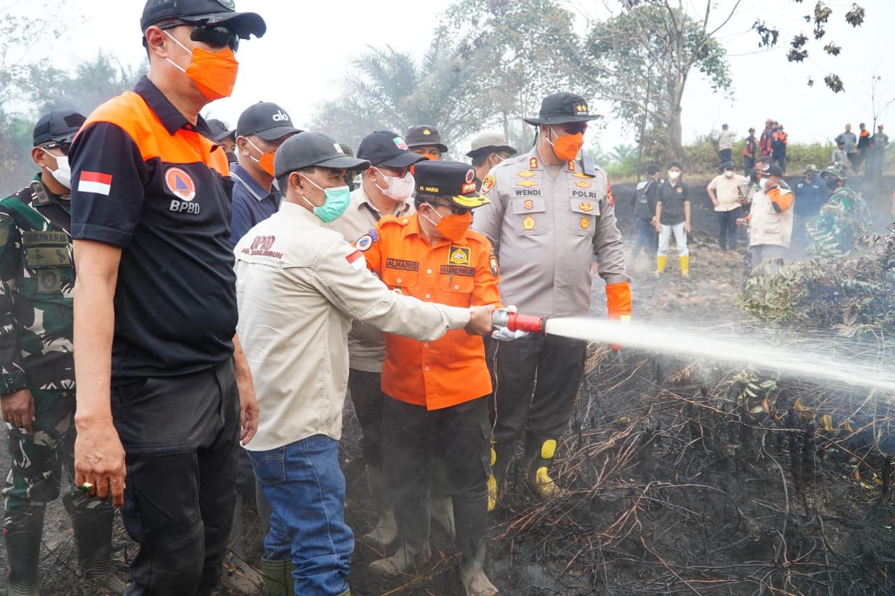 alt="Gubernur Jambi Al Haris memegang selang air memadamkan karhutla di Desa Lubuk Kepayang Sarolangun"