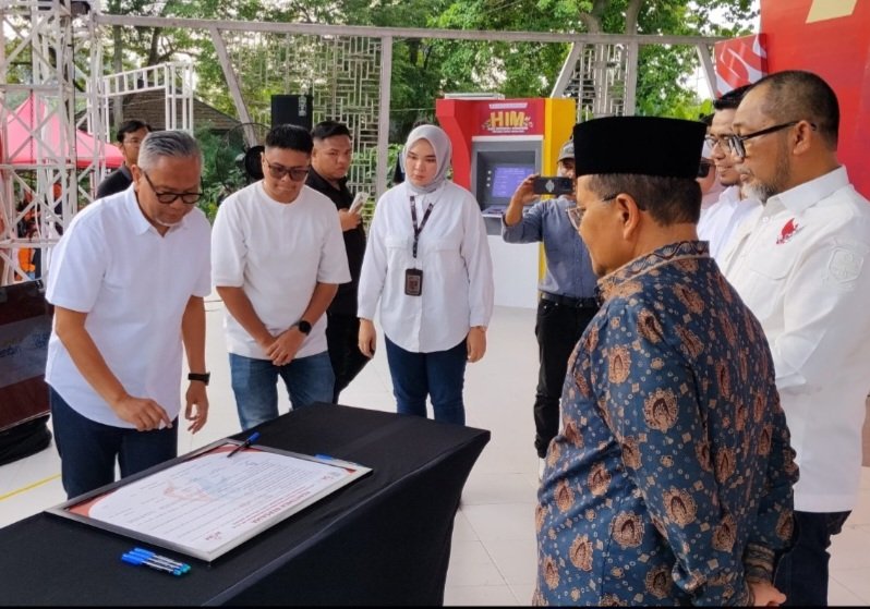 alt="Direktur Utama Bank Jambi H. Khairul Suhairi memegang trofi penghargaan OJK Jambi pada peringatan HIM 2026"
