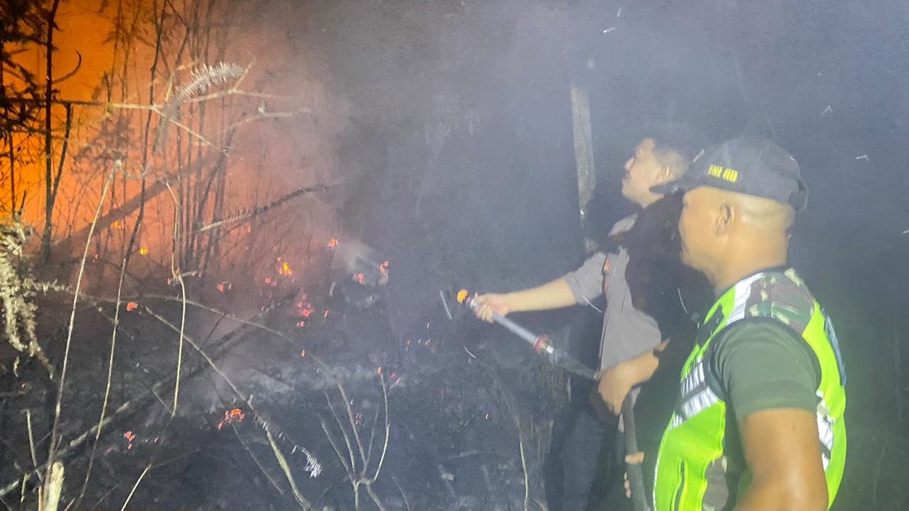 alt="Kapolsek Bajubang Iptu Yudha Rengga Permana S.Tr.K. S.I.K. M.H. menyemprotkan air ke lokasi kebakaran lahan"